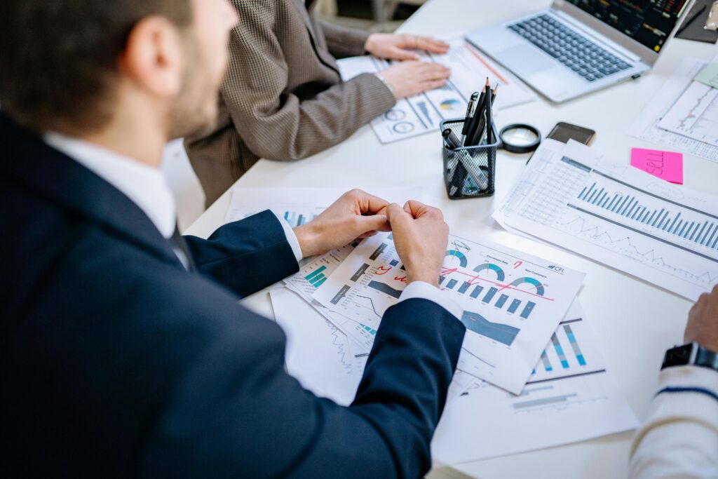 Business team analyzing financial graphs at a meeting table, fostering collaboration in an office environment.